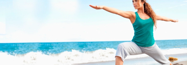 Person performing a balance and stability exercise on a beach shoreline.